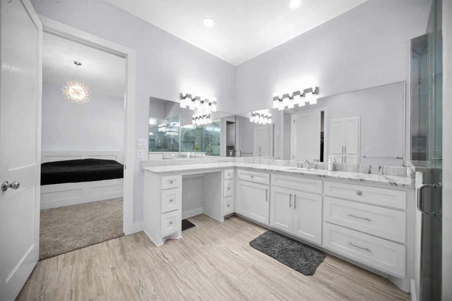 Full bathroom with ensuite bathroom, a chandelier, vanity, a shower stall, and light wood-style floors