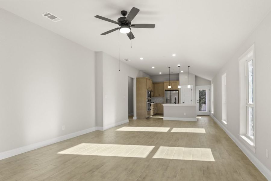 Image of a one story home living room with light wood-like flooring and light grey painted walls with two large windows and a ceiling fan Image of a one story home living room with light wood-like flooring and light grey painted walls with two large windows and a ceiling fan