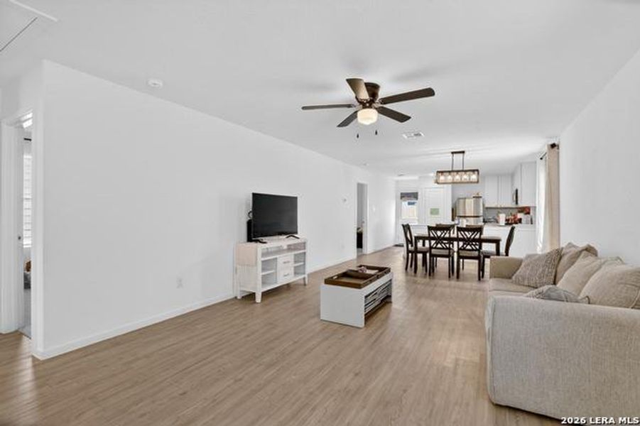 An airy living area with light wood flooring transitions seamlessly to a bright dining space and kitchen. An airy living area with light wood flooring transitions seamlessly to a bright dining space and kitchen.