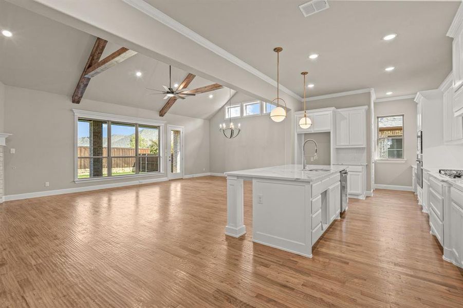 Kitchen featuring white cabinets, a ceiling fan, a kitchen island with sink, pendant lighting, and light wood finished floors