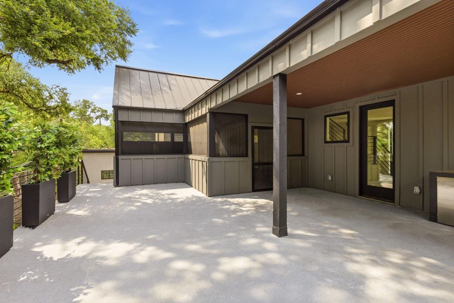 Spacious outdoor patio with a covered section, featuring a metal roof and recessed lighting