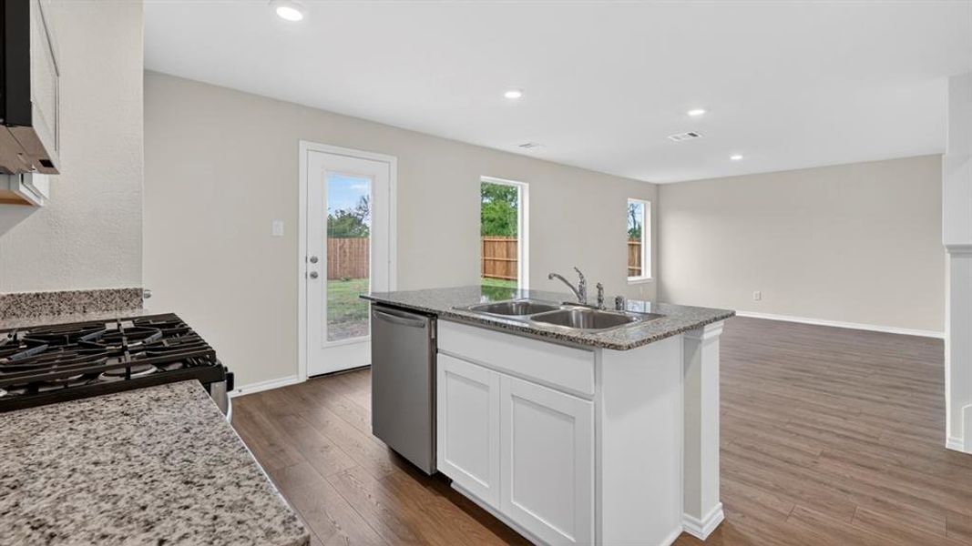 Kitchen featuring an island with a double basin sink, stainless steel dishwasher, and stone-finish countertops