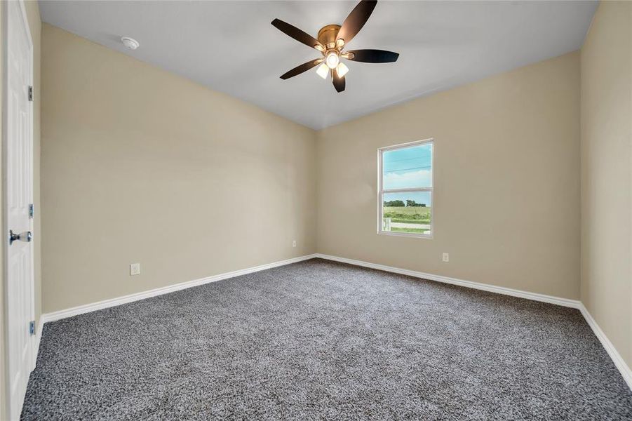 Carpeted spare room featuring ceiling fan