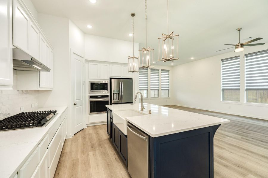 Breakfast bar featuring a classic farmhouse sink, high-end stainless steel dishwasher, and extensive custom cabinetry for ample storage.