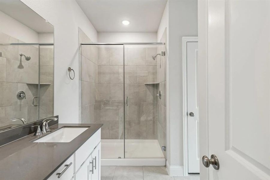 Bathroom featuring vanity, tile patterned floors, and a shower with shower door