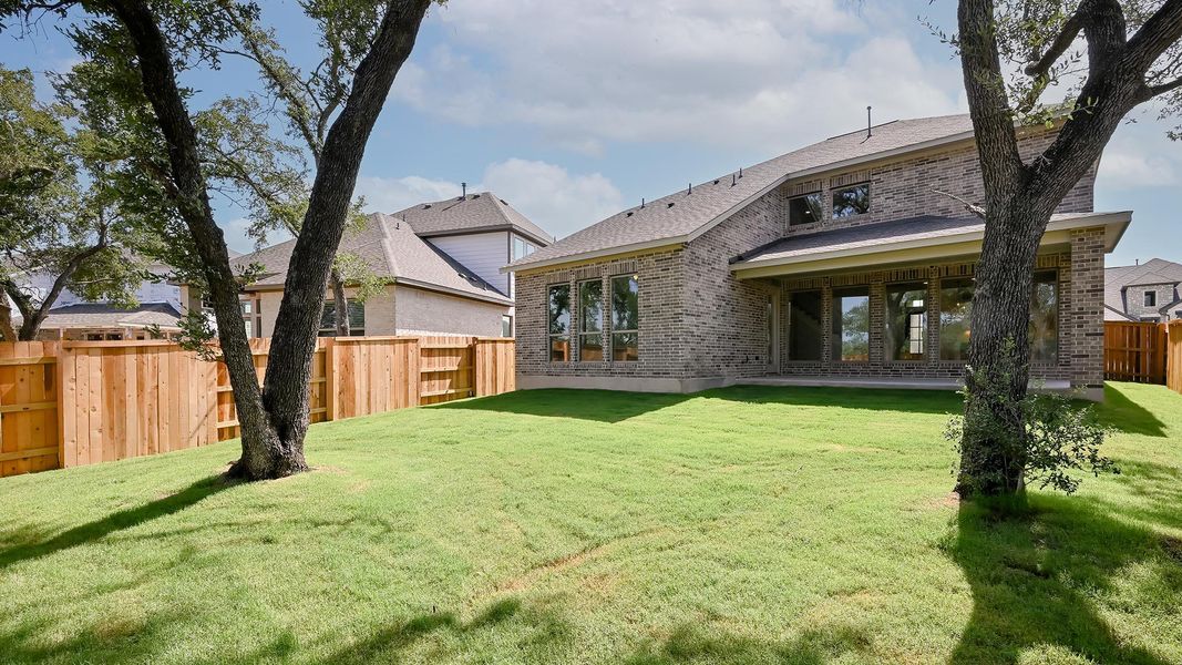 Back of property featuring brick siding, a fenced backyard, and a shingled roof