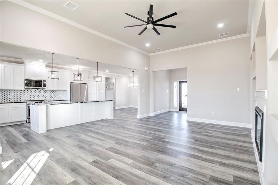 Unfurnished living room featuring crown molding, a fireplace, light wood-style flooring, a ceiling fan, and recessed lighting