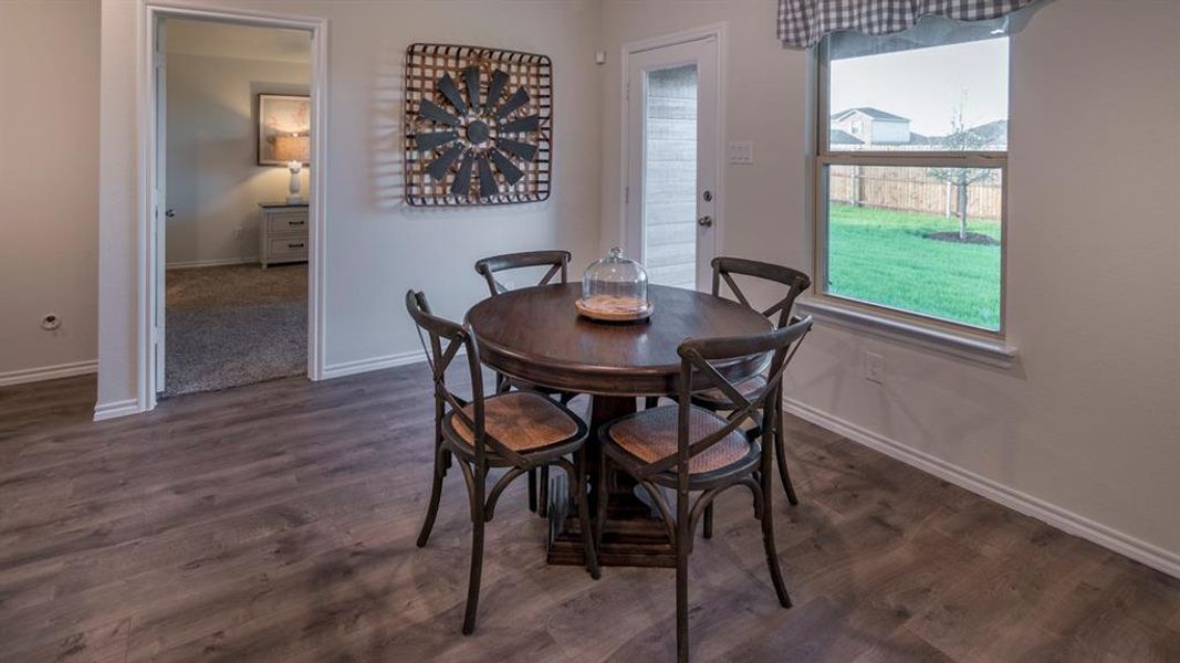 Wood-finish flooring throughout, featuring a bright window with backyard views, and a glass-paneled door providing exterior access