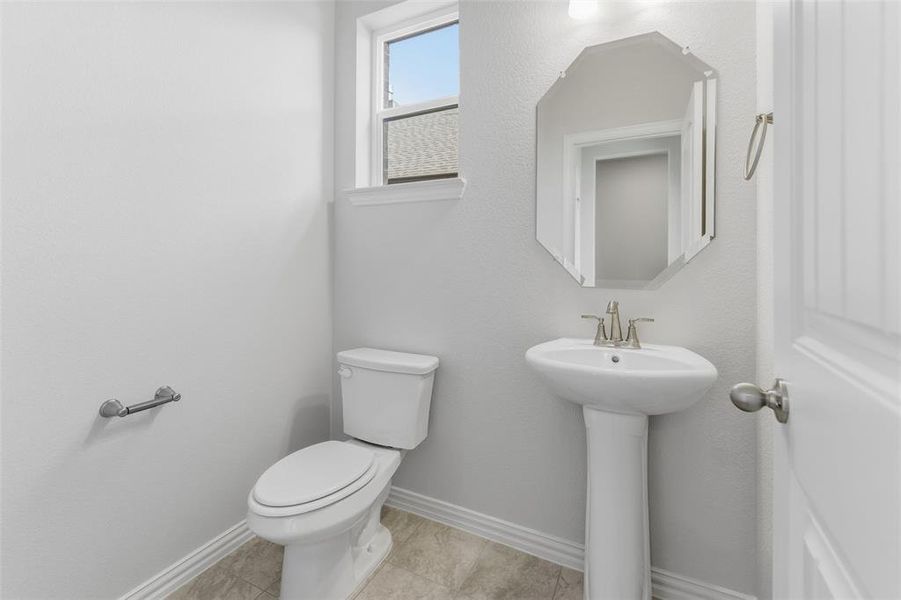 Half bath featuring baseboards and light tile patterned floors