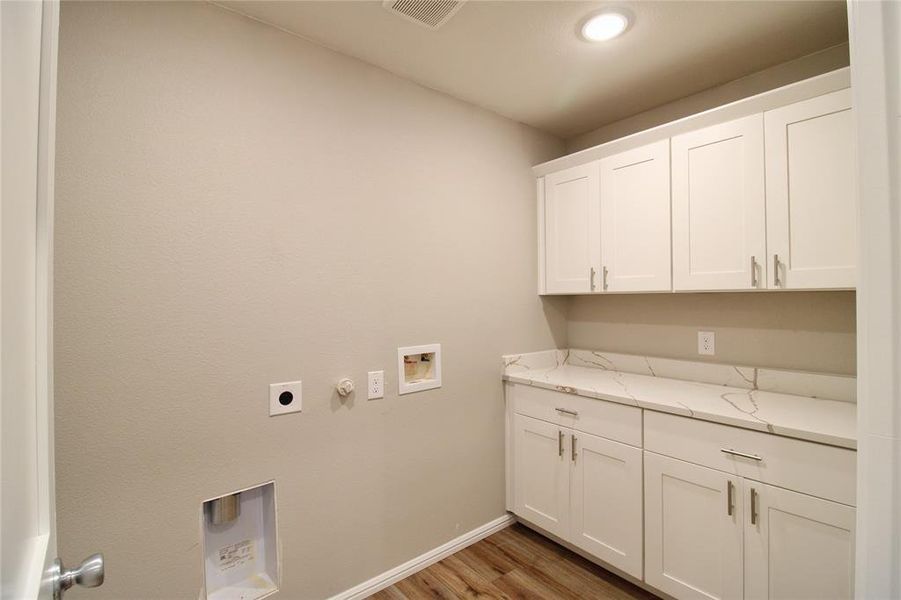 Laundry area featuring light wood-type flooring, hookup for a gas dryer, hookup for a washing machine, cabinet space, and electric dryer hookup