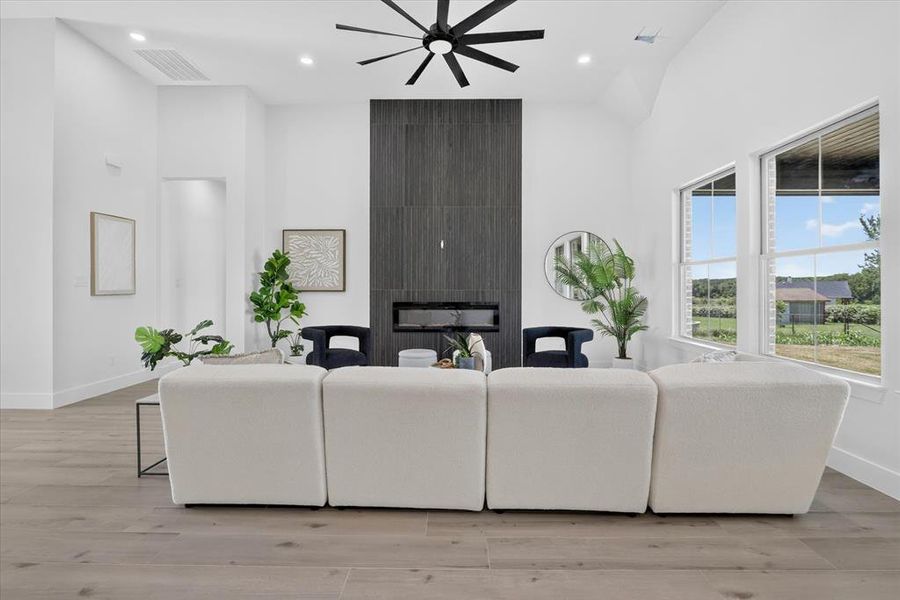 Living area featuring a floor-to-ceiling fireplace with dark tile surround, integrated linear firebox, and a black ceiling fan