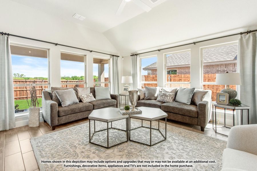 Bright living room with vaulted ceiling, two gray sofas, hexagonal coffee tables, and large windows overlooking a backyard. Bright living room with vaulted ceiling, two gray sofas, hexagonal coffee tables, and large windows overlooking a backyard.