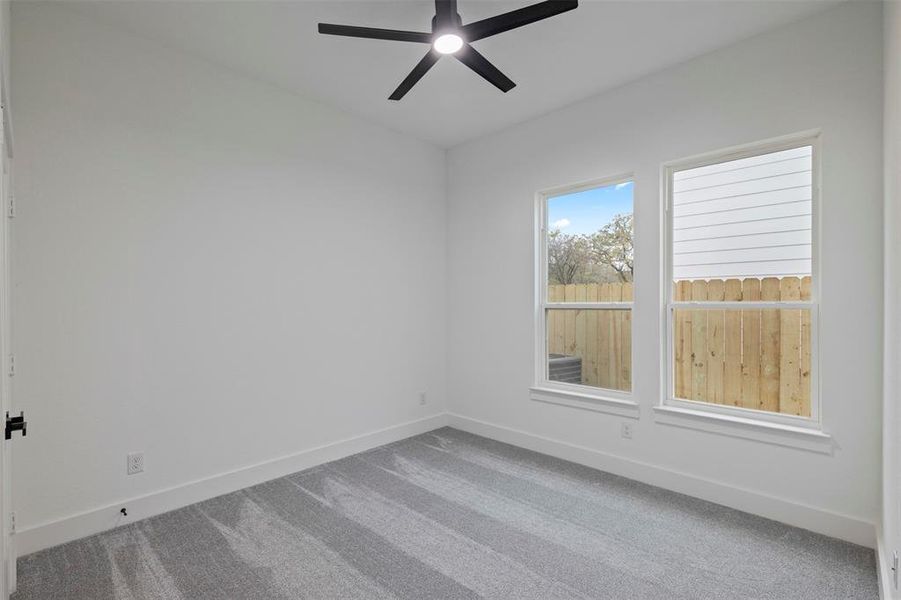 Carpeted spare room featuring baseboards and ceiling fan