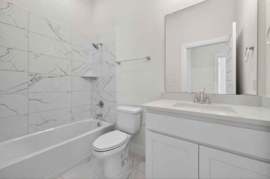 Bathroom featuring shower / bathtub combination, vanity, and light marble finish floors