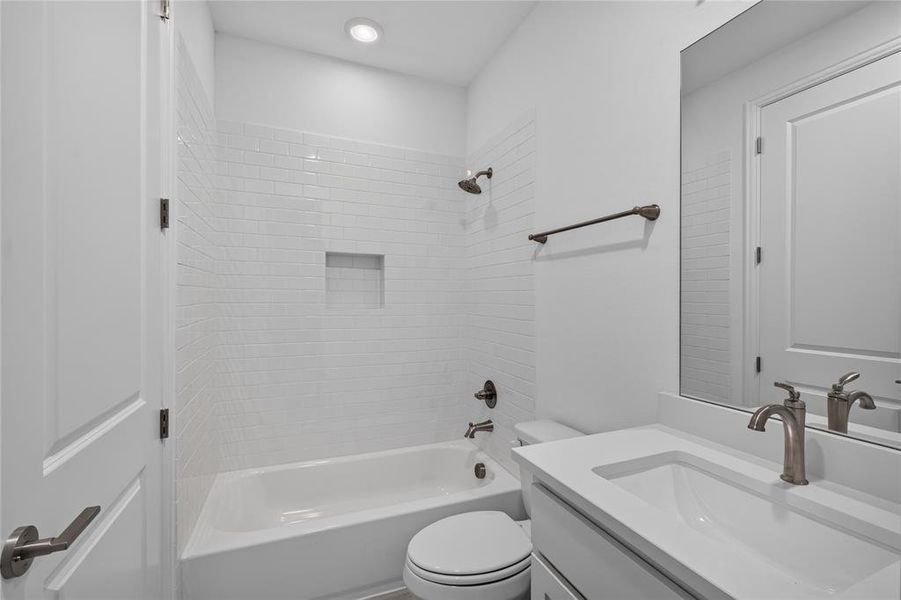 Bathroom featuring a white subway tile shower surround with a built-in niche, a white soaking tub, and a vanity with an integrated sink and brushed nickel faucet Bathroom featuring a white subway tile shower surround with a built-in niche, a white soaking tub, and a vanity with an integrated sink and brushed nickel faucet