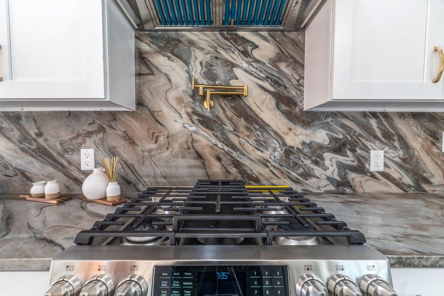 Marble backsplash with 5 burner gas stove and pot filler