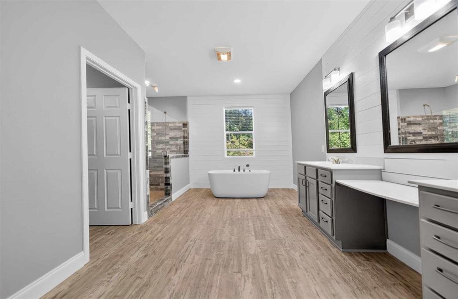 Bathroom featuring vanity, a freestanding bath, light wood-style flooring, a stall shower, and wooden walls