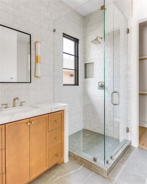 Bathroom with tile walls, tile patterned flooring, vanity, and a shower with shower door