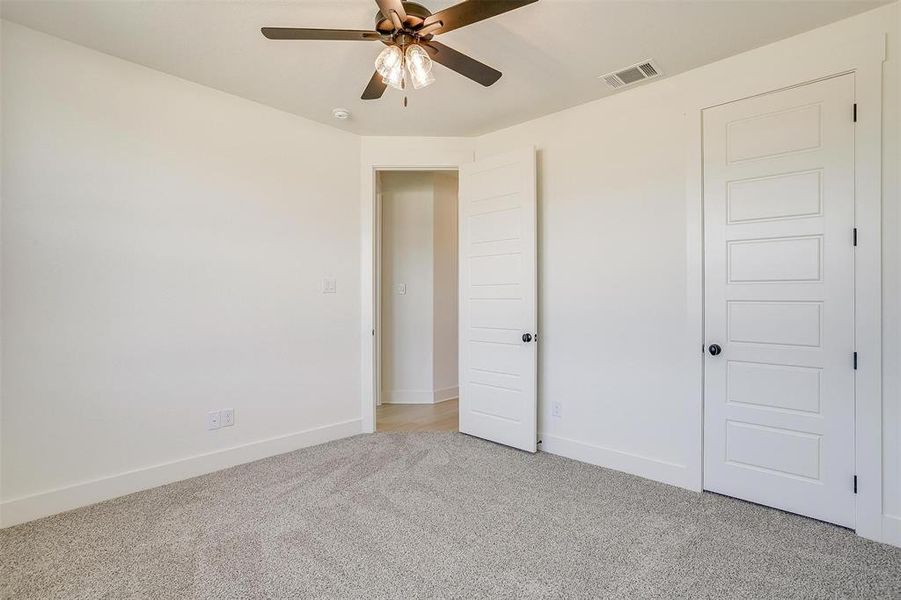 Unfurnished bedroom with ceiling fan and light colored carpet