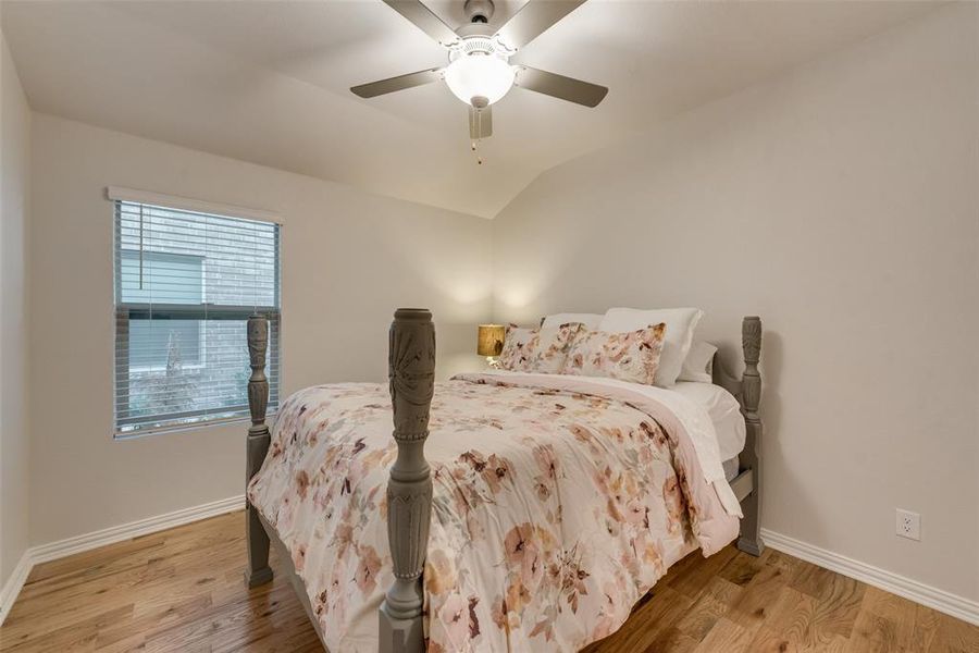 Bedroom featuring ensuite bathroom, lofted ceiling, ceiling fan and hardwood flooring