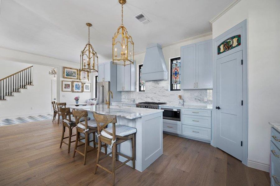 Kitchen featuring a kitchen bar, dark wood-type flooring, a center island, light stone countertops, and decorative backsplash