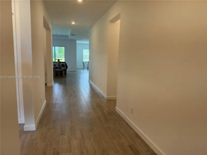 Interior hallway featuring wood-finish tile flooring, recessed lighting, and high ceilings
