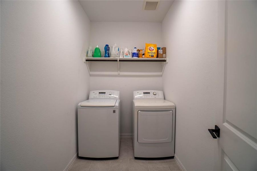 Dedicated laundry area featuring a built-in shelf, light-toned wall paint, and tile flooring