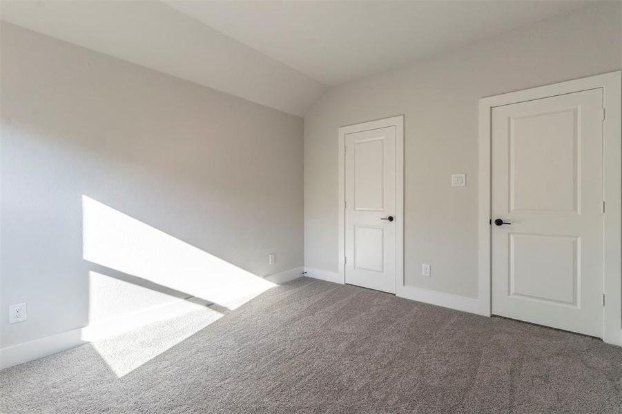 Unfurnished bedroom with carpet floors and vaulted ceiling