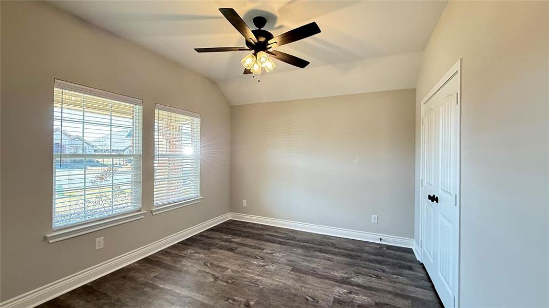 Empty room with lofted ceiling, dark hardwood / wood-style flooring, and ceiling fan