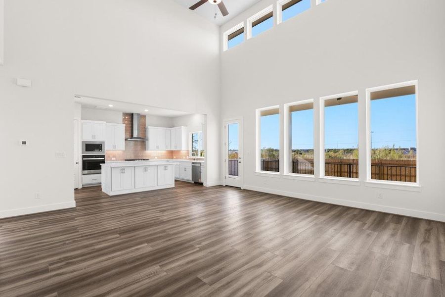 Unfurnished living room featuring dark wood-style floors, a ceiling fan, and a towering ceiling Unfurnished living room featuring dark wood-style floors, a ceiling fan, and a towering ceiling