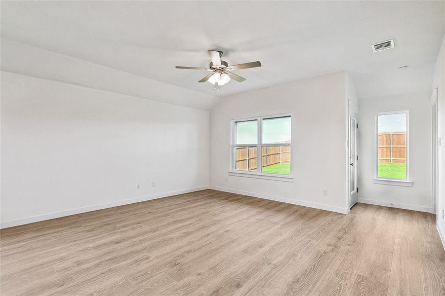 Empty room with ceiling fan, light hardwood / wood-style floors, and vaulted ceiling