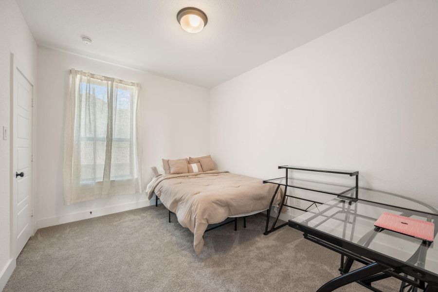 A well-lit bedroom provides a serene escape, featuring soft carpeting and a window for natural light. A well-lit bedroom provides a serene escape, featuring soft carpeting and a window for natural light.
