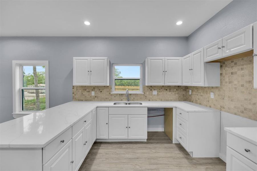 Kitchen featuring a peninsula, light wood-type flooring, white cabinets, and recessed lighting