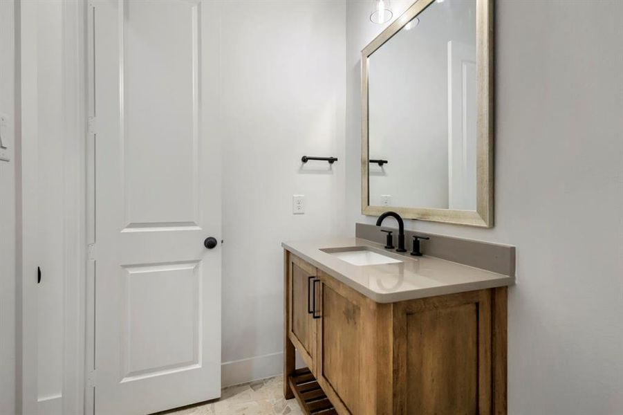 Bathroom featuring a wooden vanity with a light-colored countertop and an undermount sink