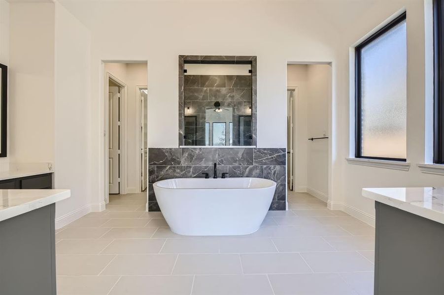 Bathroom featuring tile patterned flooring, separate shower and tub, vaulted ceiling, tile walls, and vanity