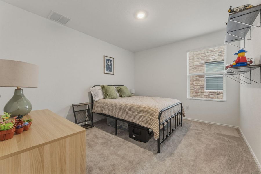 Bedroom featuring light gray carpet flooring, white walls, and a window providing natural light