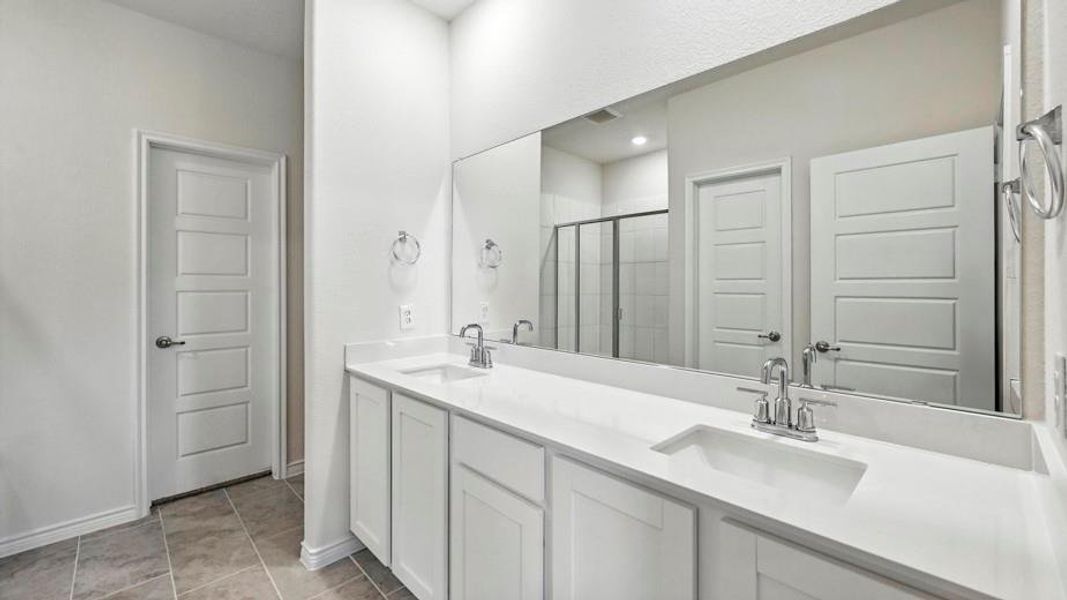 Bathroom featuring a double vanity with white cabinetry, white countertops, and chrome fixtures