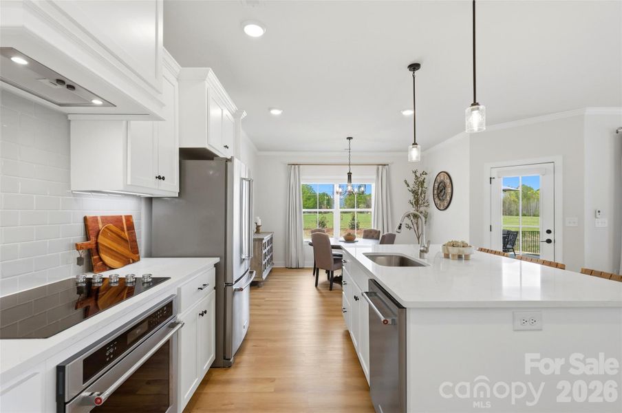 This beautifully designed kitchen features crisp white cabinetry and quartz countertops.