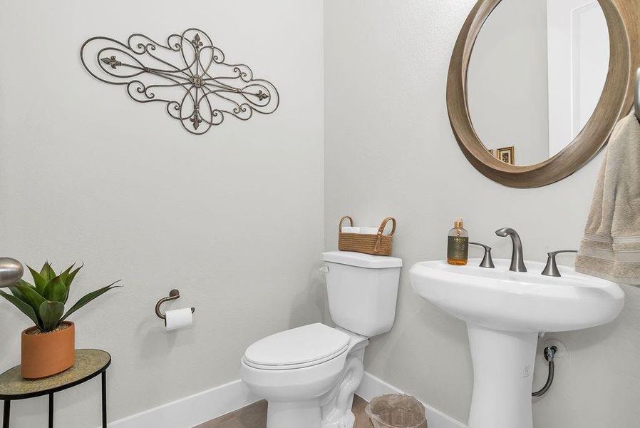Powder bath with pedestal sink with brushed nickel fixtures and a wood-framed mirror