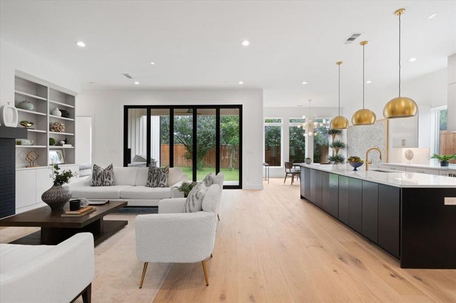 Living room with a notable chandelier, sink, and light hardwood / wood-style floors