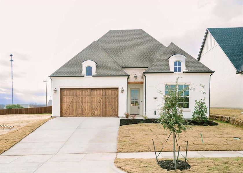 French provincial home featuring a garage and a front lawn