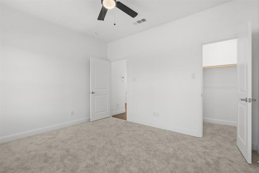 Unfurnished bedroom with ceiling fan, light colored carpet, a walk in closet, and a closet