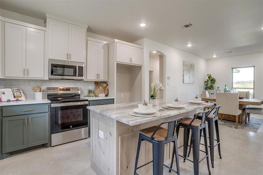 Kitchen with a center island, appliances with stainless steel finishes, light stone counters, and white cabinetry