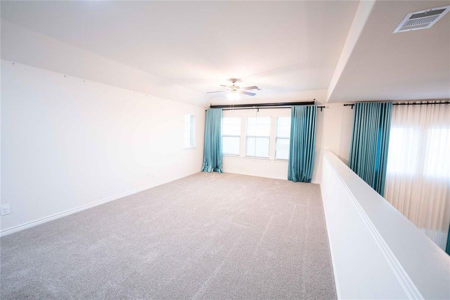 Spacious upper-level room featuring light gray carpeting and white walls Spacious upper-level room featuring light gray carpeting and white walls