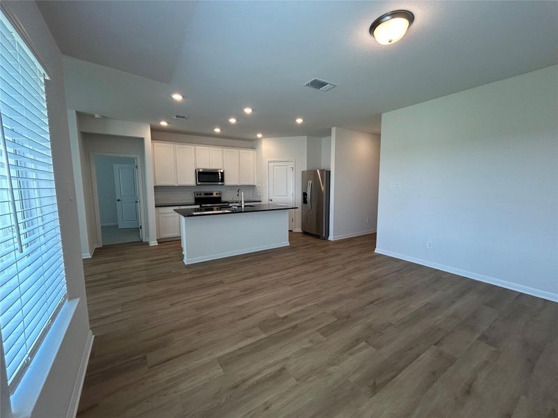 Kitchen featuring dark countertops, dark wood-style floors, open floor plan, stainless steel appliances, and an island with sink Kitchen featuring dark countertops, dark wood-style floors, open floor plan, stainless steel appliances, and an island with sink