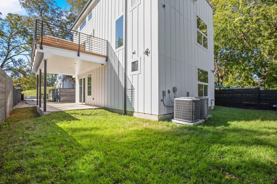Rear view of property featuring board and batten siding, a fenced backyard, and a patio Rear view of property featuring board and batten siding, a fenced backyard, and a patio