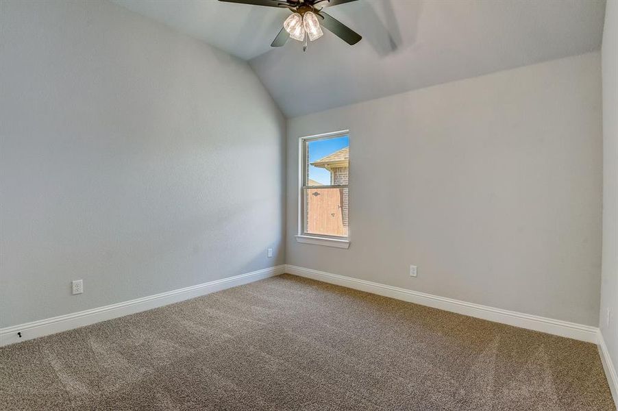 Unfurnished room featuring carpet floors, ceiling fan, and vaulted ceiling