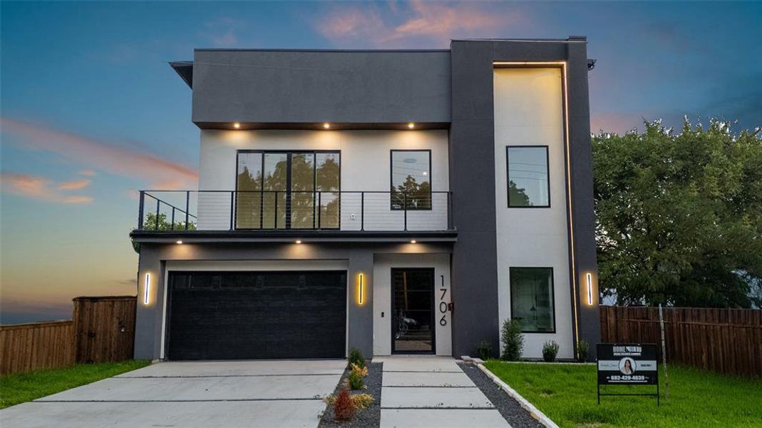 Contemporary home with stucco siding, driveway, an attached garage, and a balcony