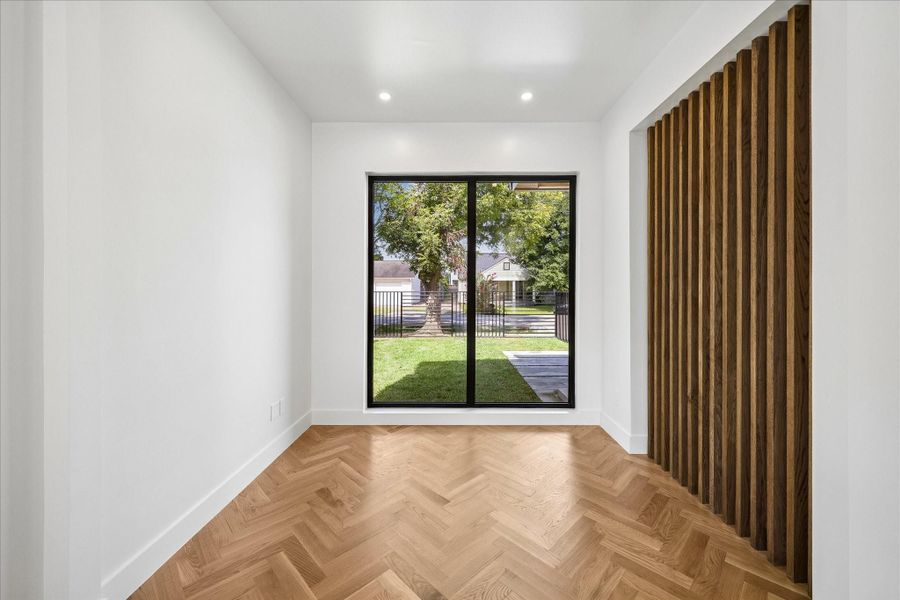 Study with herringbone wood flooring and large windows offering a view of the lush backyard, complemented by stylish vertical wood paneling. Study with herringbone wood flooring and large windows offering a view of the lush backyard, complemented by stylish vertical wood paneling.