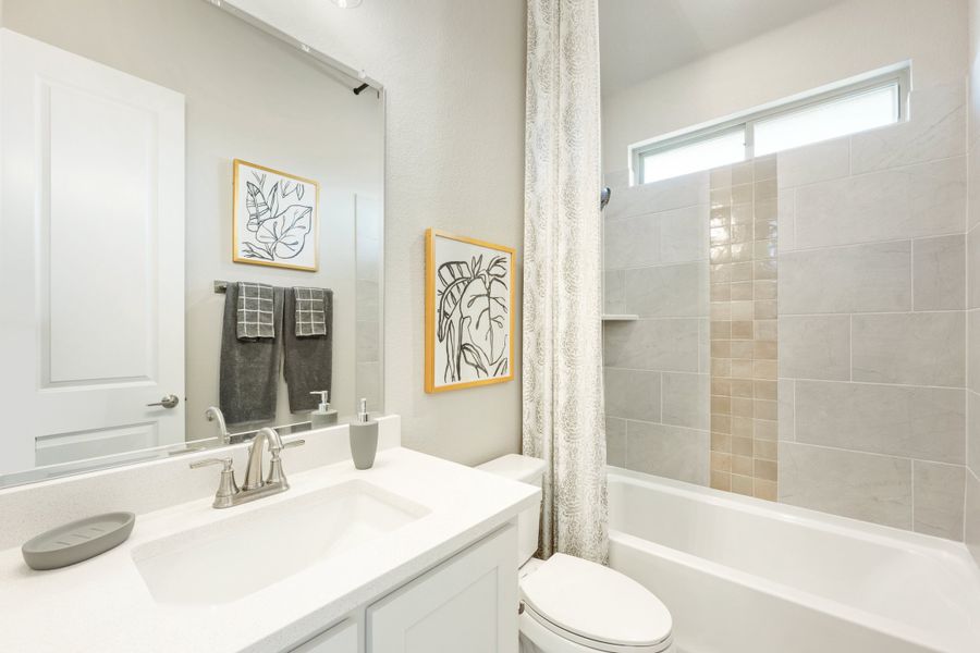 Bathroom with white vanity, tub-shower combo with tile surround, and large mirror Bathroom with white vanity, tub-shower combo with tile surround, and large mirror
